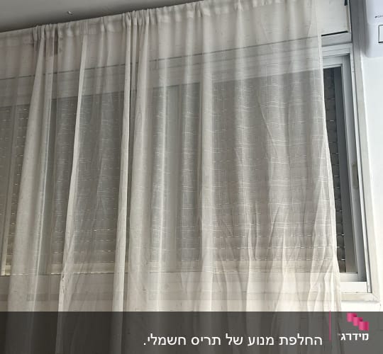 חלון עם תריסים סגורים מאחורי וילון שקוף